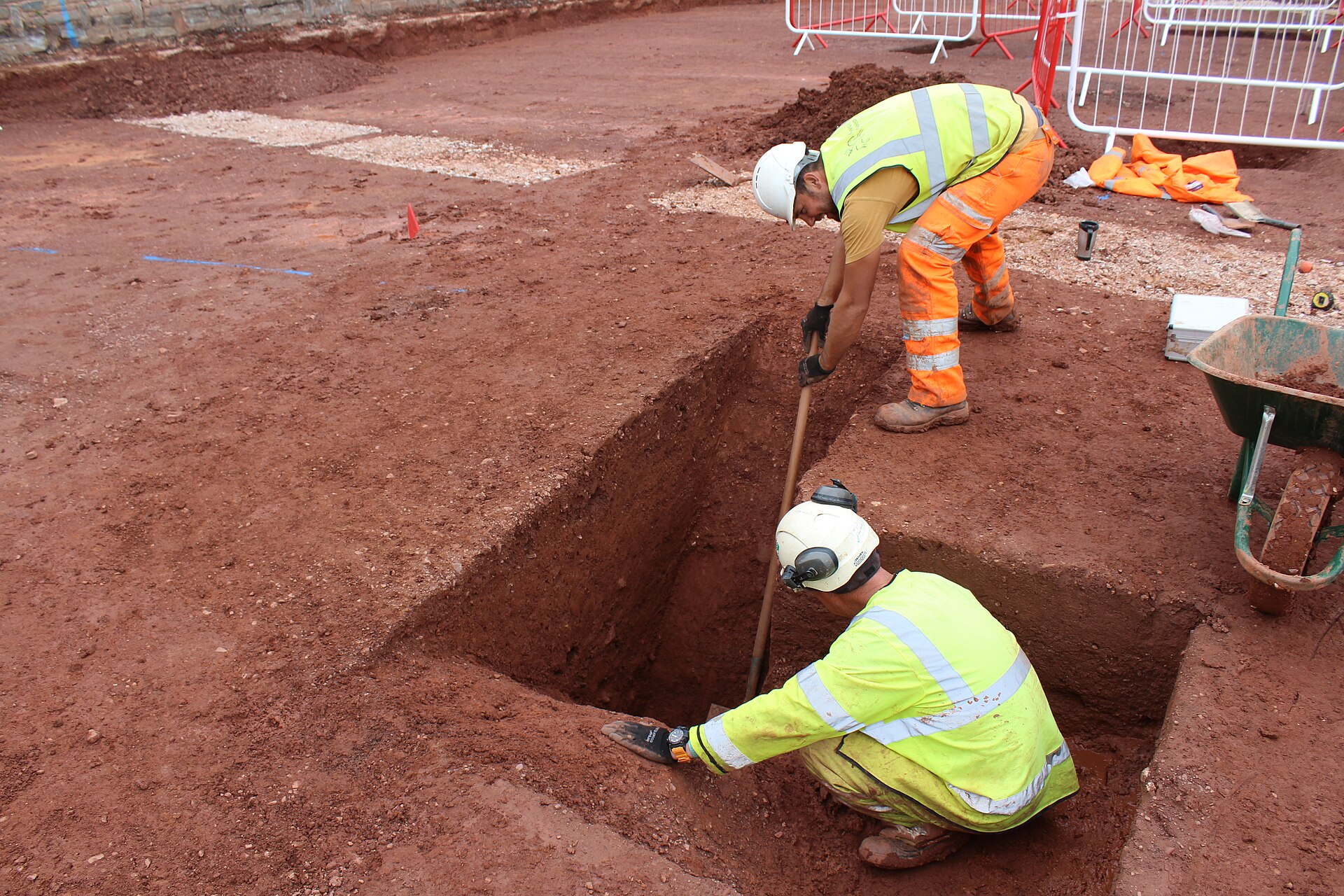 Archaeologists excavating a stone-lined trench